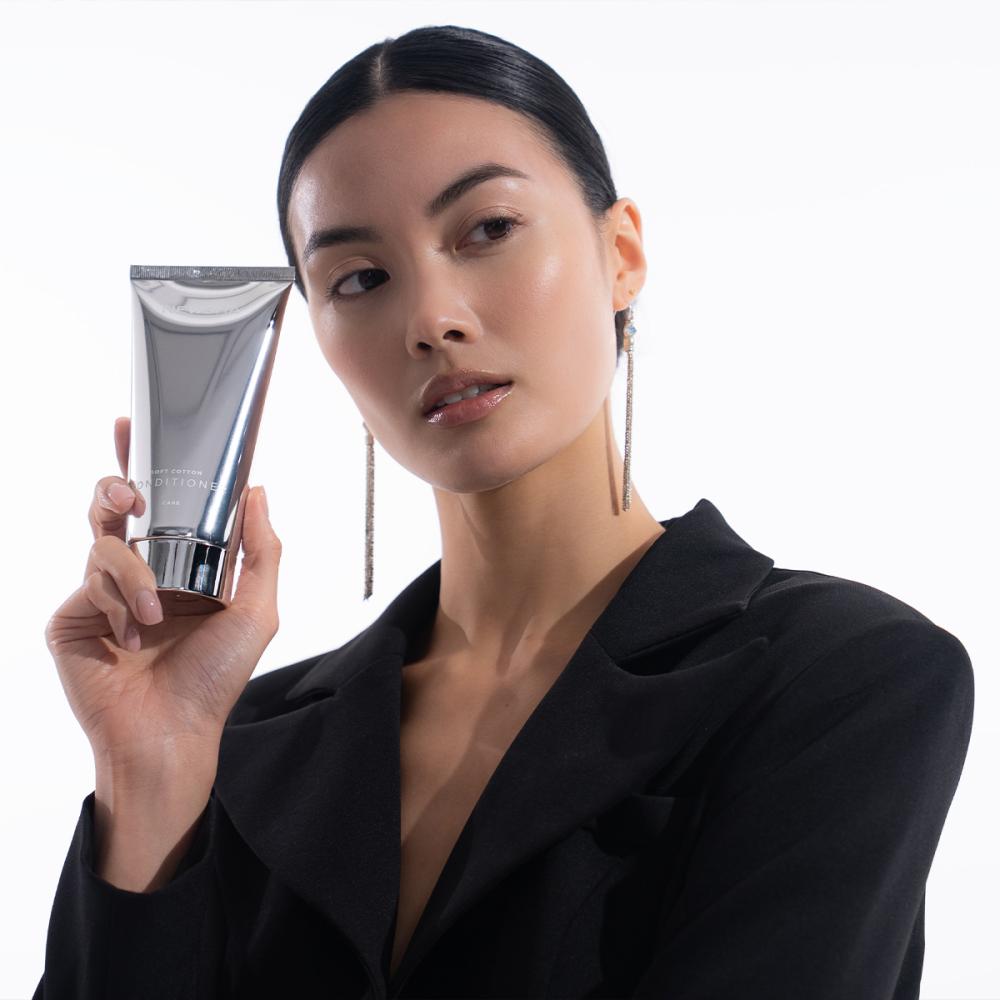 Porträt einer blonden Frau mit weichen Beach Waves im warmen Sonnenlicht. Sie trägt ein champagnerfarbenes Satin-Top und blickt direkt in die Kamera; sanfte Schatten verleihen dem Beauty-Motiv eine elegante, sommerliche Atmosphäre.