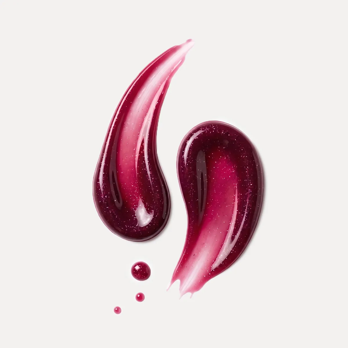 Zwei gl&auml;nzende, dunkelrot-pinke Farbtexturen mit feinen Schimmerpartikeln und kleinen Tropfen auf hellem Hintergrund.