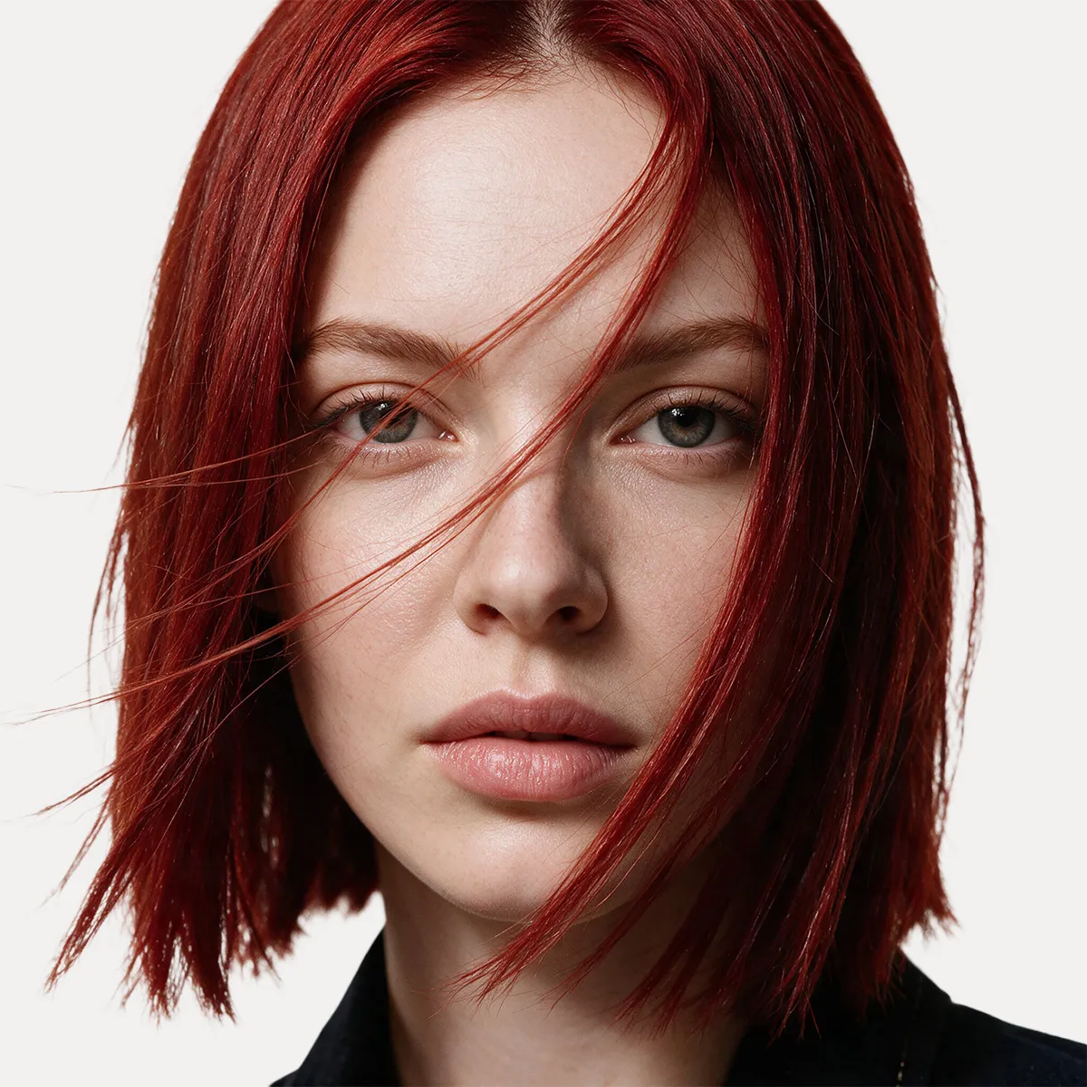Model mit intensiv rotem, glänzendem Bob und glatter Haarstruktur. Leicht bewegte Strähnen unterstreichen die leuchtende Haarfarbe.